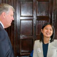 two alumni shake hands with President Haas